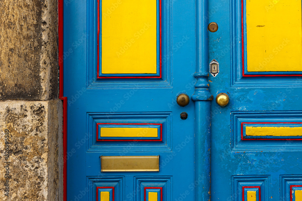 Old wooden blue and yellow door with metal door handle. Architectural textured background Old wooden blue and yellow door with metal door handle. Architectural textured background