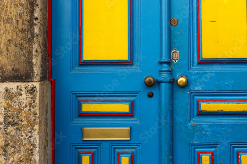 Old wooden blue and yellow door with metal door handle. Architectural textured background