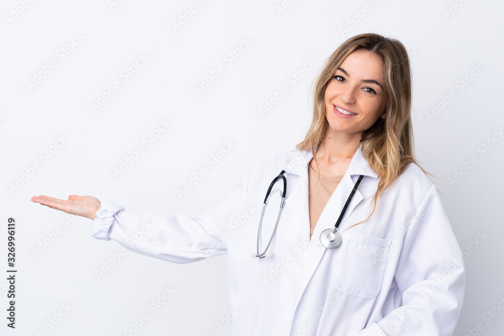 Young woman over isolated white background wearing a doctor gown and presenting something Young woman over isolated white background wearing a doctor gown and presenting something