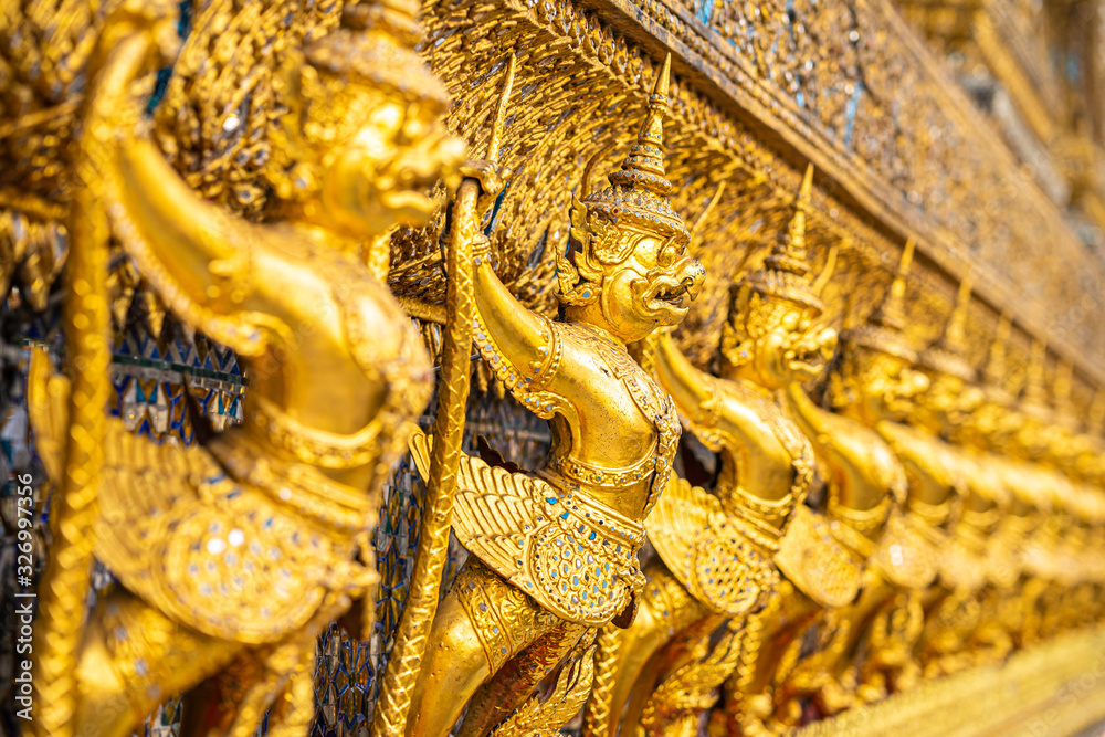 The Golden Garuda and Naga Statue Decorated with colored glass On the wall of the Buddhist temple at Emerald Buddha Temple And the royal palace Bangkok, Thailand The Golden Garuda and Naga Statue Decorated with colored glass On the wall of the Buddhist temple at Emerald Buddha Temple And the royal palace Bangkok, Thailand