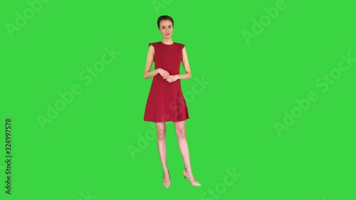 Pretty woman in a dress talking and making gestures like in weather forecast on a Green Screen, Chroma Key. photo