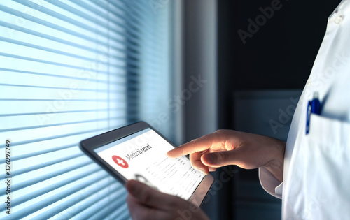 Doctor using electronic medical record (EMR) in tablet to read health care information for patient. Digital healthcare history or report. Cardiology research. Surgeon or specialist with smart device. photo