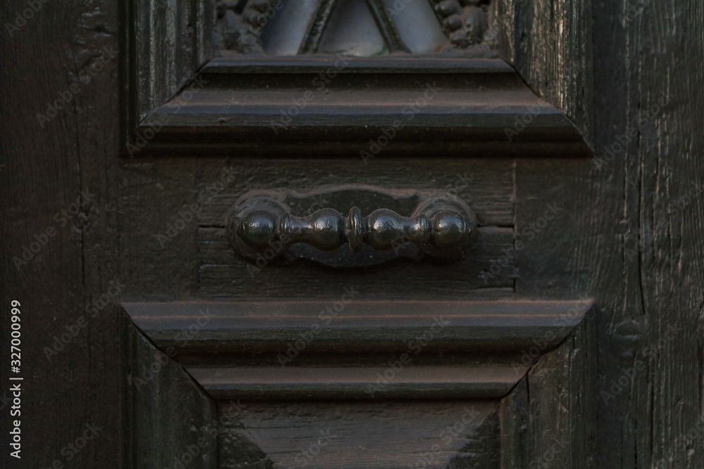 Wooden dark aged textured entrance with rings door handles and metal details. Architecture background. Old wooden door with rivets and aged metal door handle in the form of ring Wooden dark aged textured entrance with rings door handles and metal details. Architecture background. Old wooden door with rivets and aged metal door handle in the form of ring