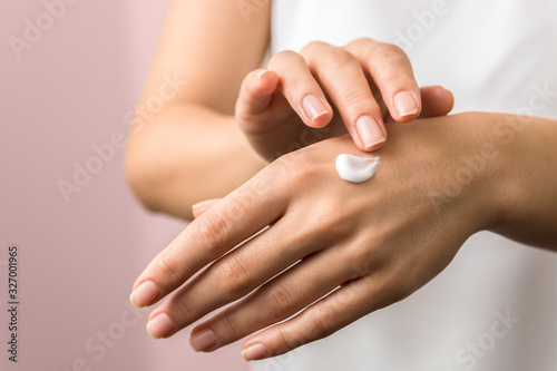 closeup of tender hands of a young woman with moisturizer on. spring skin protection