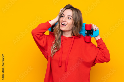 Young woman over isolated yellow background with a skate and looking up