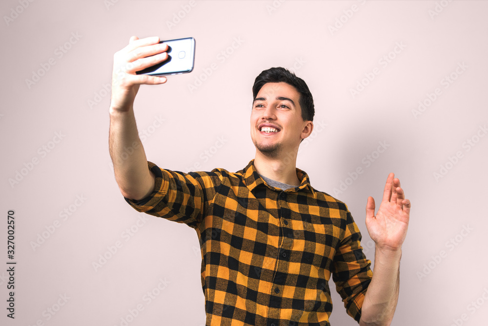 good looking young man in casual yellow shirt video-chatting via smartphone isolated on background good looking young man in casual yellow shirt video-chatting via smartphone isolated on background