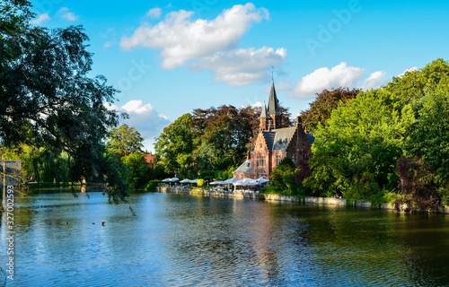 Bruges, Belgium. August 2019. The lake and minnewater park are the most romantic place. The body of water on which the red brick castle and the large trees with green foliage are reflected. © Massimo Parisi