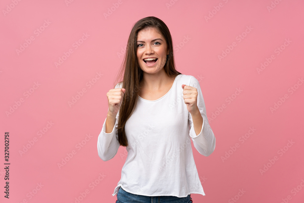 Young woman over isolated pink background celebrating a victory in winner position Young woman over isolated pink background celebrating a victory in winner position