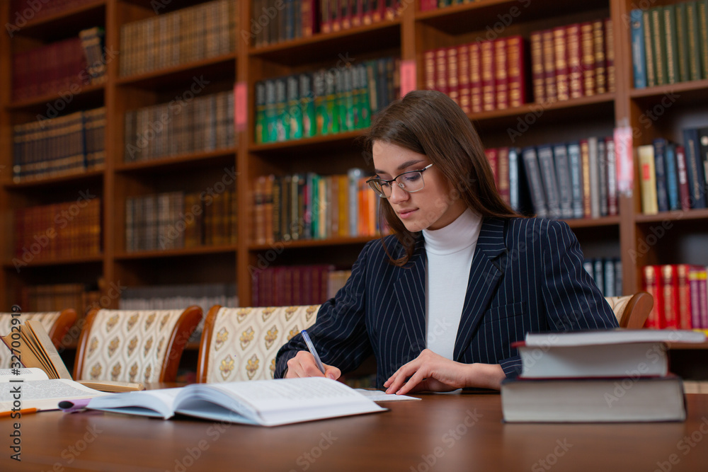 The girl student in the library does homework The girl student in the library does homework