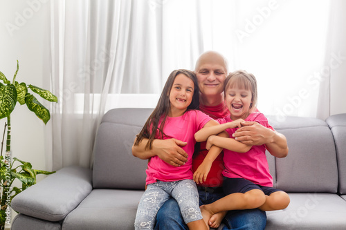 Mature man playing with granddaughters at home.