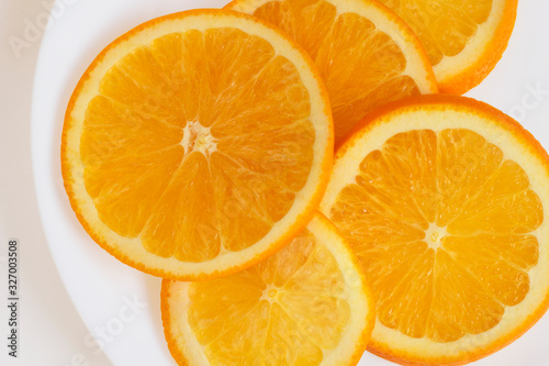 Top view of a plate with sliced orange on white background.