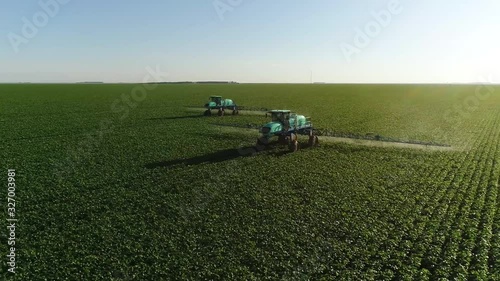 Agriculture, beautiful aerial image of machines spraying soybean plantation in the open field with circular motion - Agribusiness.