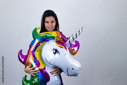 happy pretty  middle age woman model with unicorn balloon smiling, isolated on gray background studio shotblack sweater, denim jacket, jeans. Place for your text in copy space. photo