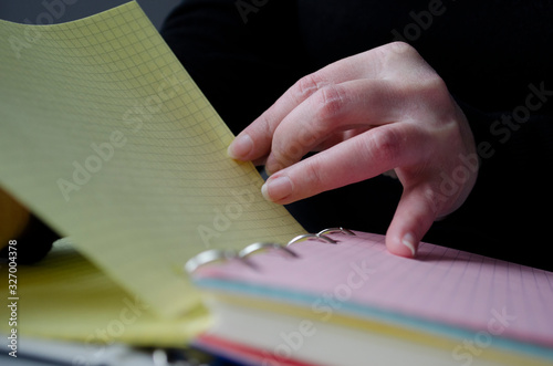 A person reading books near the window. Hands turns over book page. photo