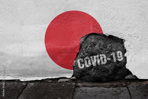 Flag of Japan on the wall with cracked stone with Coronavirus name on it. 2019 - 2020 Novel Coronavirus (2019-nCoV) concept, for an outbreak occurs in Japan. photo