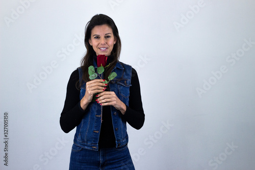 happy pretty  middle age woman model with rose smiling, isolated on gray background studio shotblack sweater, denim jacket, jeans. Place for your text in copy space. photo