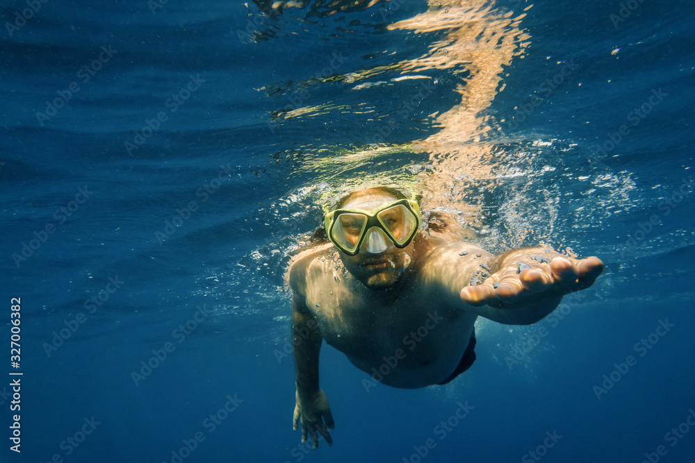 Male diver in blue water. Open sea, ocean, swimming, active travel and underwater diving concept.