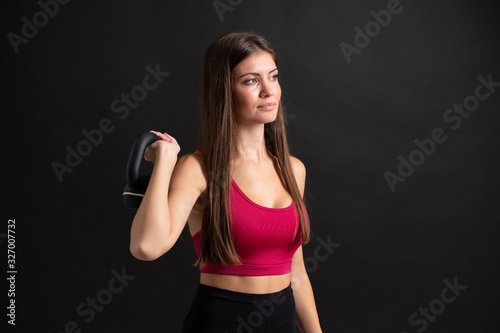 Young sport woman making weightlifting over isolated black background