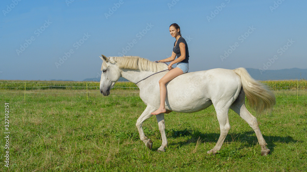Fototapeta premium Girl on beautiful white horse bareback riding on grass field