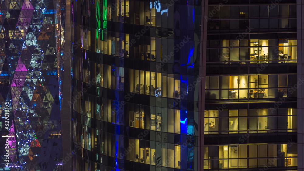 Windows timelapse of the multi-storey building of glass and steel office lighting and working people within