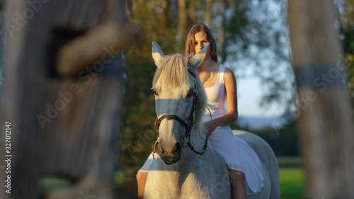 CLOSE UP: Pretty girl in white dress bareback riding beautiful white stallion