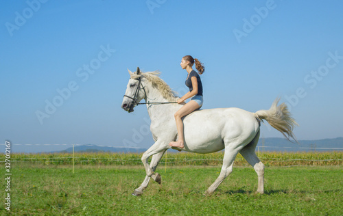 Young woman running bareback with her beautiful white horse