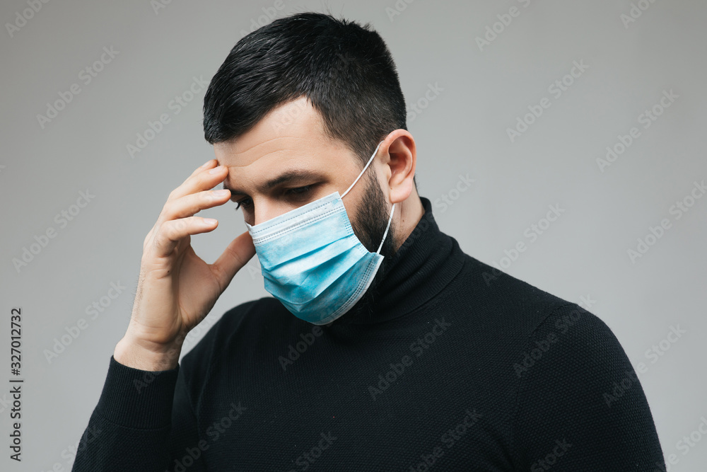 Man wear mask with eye frown, holds hands on head, headache. Man wearing protection face mask against coronavirus. Banner panorama medical staff preventive gear Man wear mask with eye frown, holds hands on head, headache. Man wearing protection face mask against coronavirus. Banner panorama medical staff preventive gear