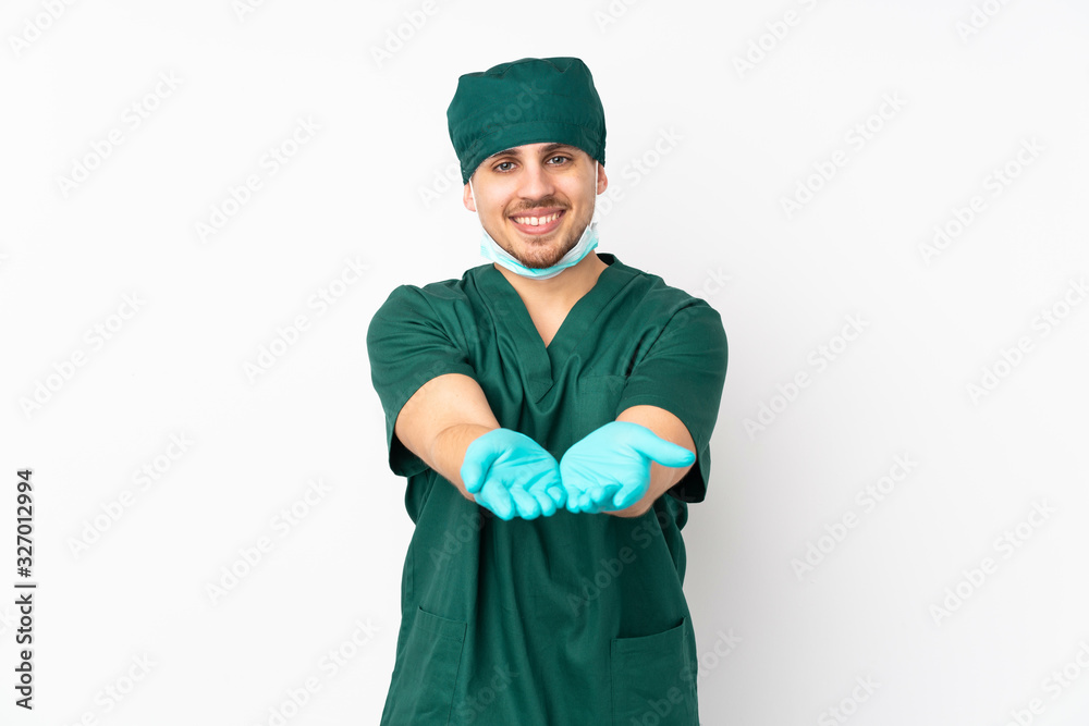 Surgeon in green uniform isolated on isolated white background holding copyspace imaginary on the palm to insert an ad Surgeon in green uniform isolated on isolated white background holding copyspace imaginary on the palm to insert an ad
