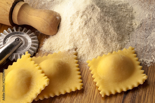 Ravioli su tavolo di lavoro con farina e attrezzi da cucina photo