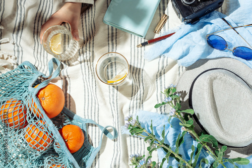 Feminine summer picnic flatlay, fruits, berries and lemon water on striped cotton blanket