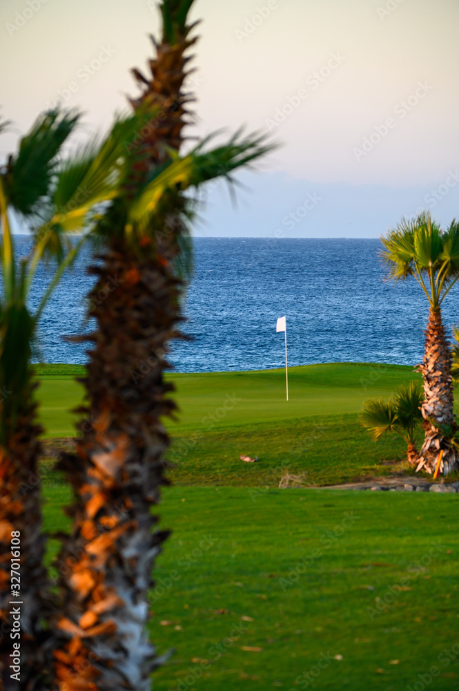 View on evergreen grass field on large golf course and blue Atlantic ocean on Tenerife island, Canary, Spain View on evergreen grass field on large golf course and blue Atlantic ocean on Tenerife island, Canary, Spain