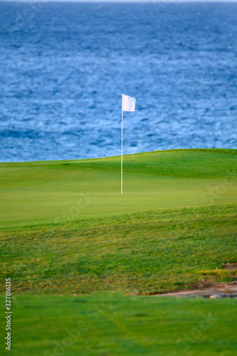 View on evergreen grass field on large golf course and blue Atlantic ocean on Tenerife island, Canary, Spain