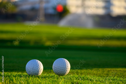 Excellent well-kept green grass lawn on large golf course, green section with big white foam balls for beginners on Tenerife island, Canary, Spain