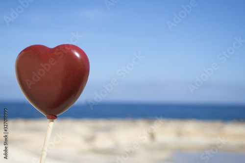 Red heart shape on sandy beach by the ocean. summer love background
