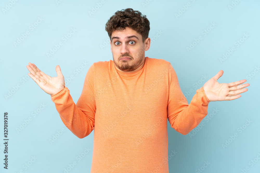 Fototapeta premium Caucasian man isolated on blue background making doubts gesture