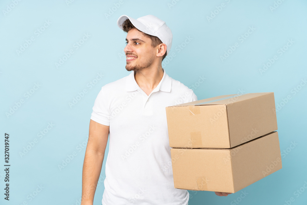 Delivery caucasian man isolated on blue background laughing