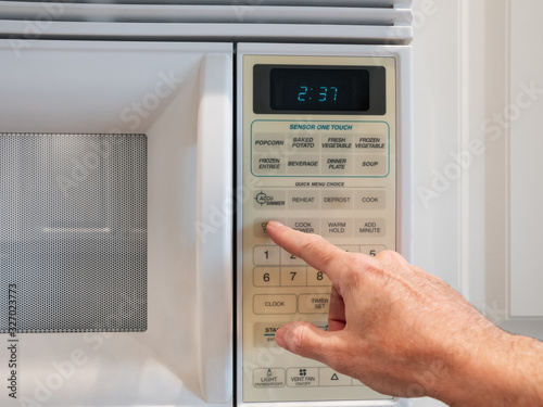 Using a digital keypad to set the microwave oven power level and microwaving time for cooking or reheating. Selecting temperature and cooking timer duration on home kitchen appliance.
