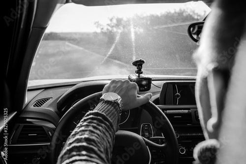The man behind the wheel of the car looks forward, his hand on the steering wheel. Black and white photo