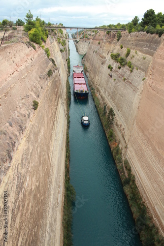 Narrow Corinth Canal between Cyprus and Greece with a tugboat and a barge in the background