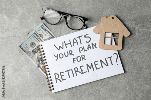 Notebook with inscription, glasses, wood house and money on grey background, top view