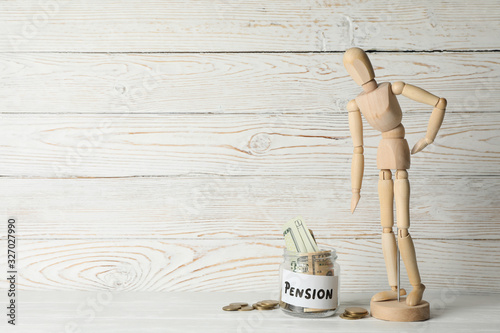 Wooden man and jar with money on wooden background, space for text