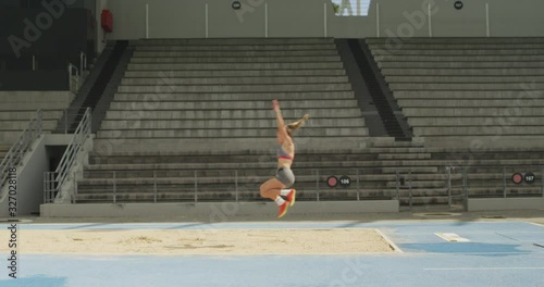 Side view of caucasian athlete doing long jump photo