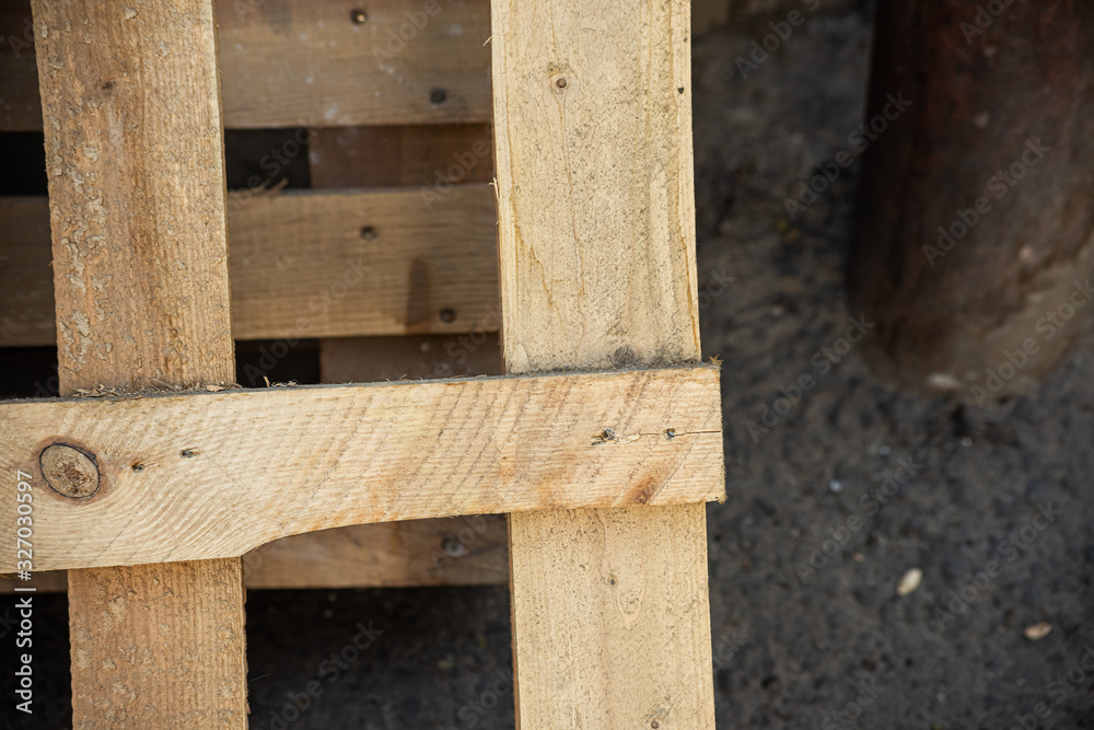 Part of a yellow wooden pallet at the metal pipe Part of a yellow wooden pallet at the metal pipe