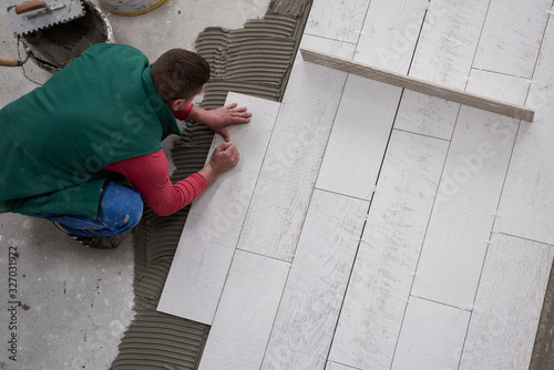 worker installing the ceramic wood effect tiles on the floor