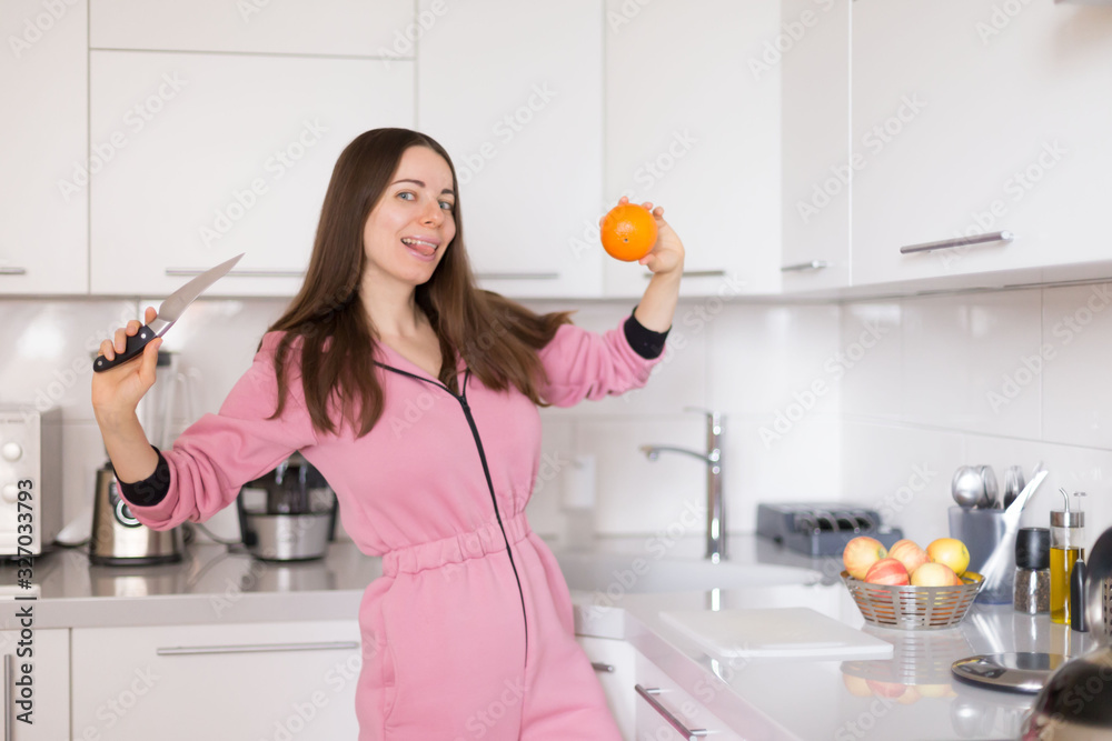 woman in pink overalls, kitchen, orange fruit woman in pink overalls, kitchen, orange fruit