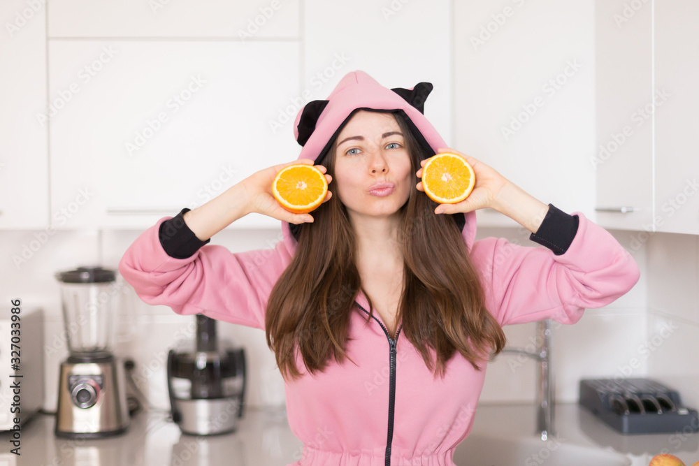 woman in pink overalls, kitchen, orange fruit woman in pink overalls, kitchen, orange fruit