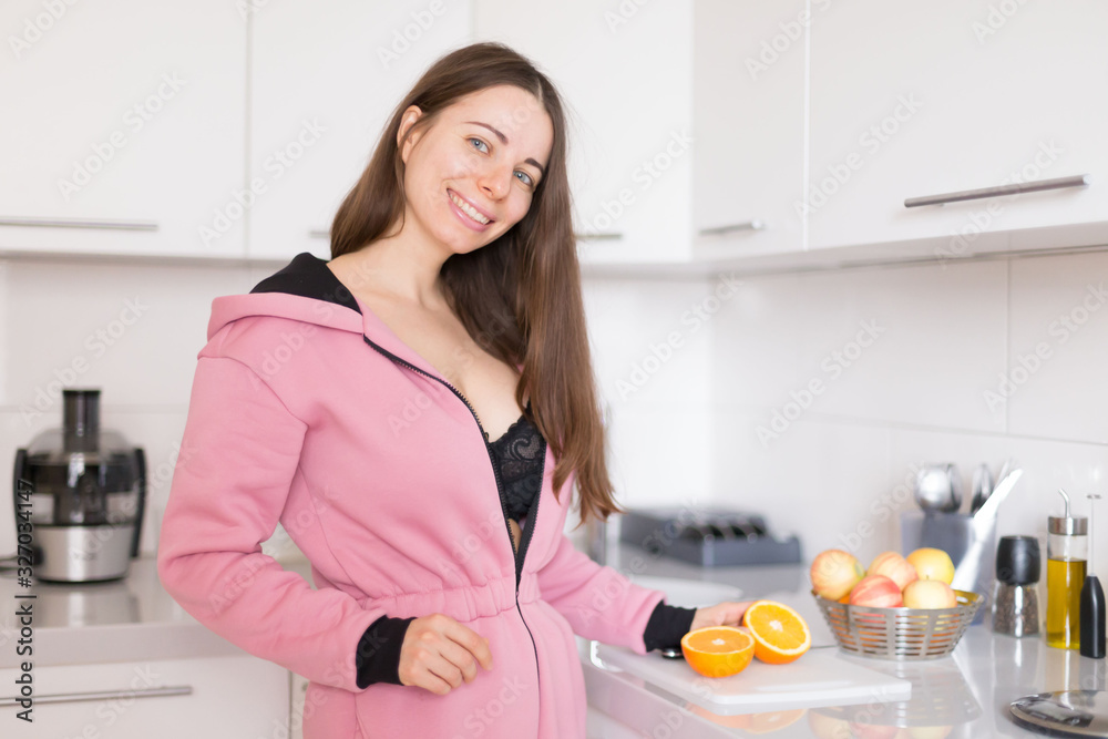 woman in pink overalls, kitchen, orange fruit woman in pink overalls, kitchen, orange fruit