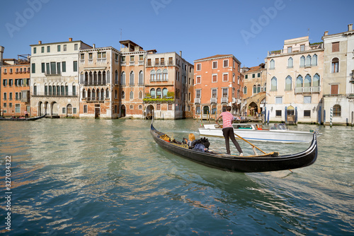 Gondolier in dance pose with a passenger in his gondola, crossing water taxi in Grand Canal, Venice, Italy © Jordanj