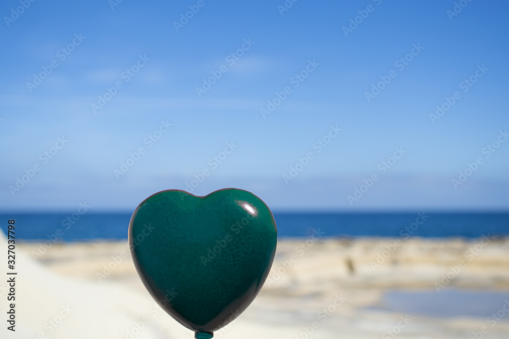 a green heart on the background of the sea. Symbol and concept of love, nature, environment, global earth a green heart on the background of the sea. Symbol and concept of love, nature, environment, global earth