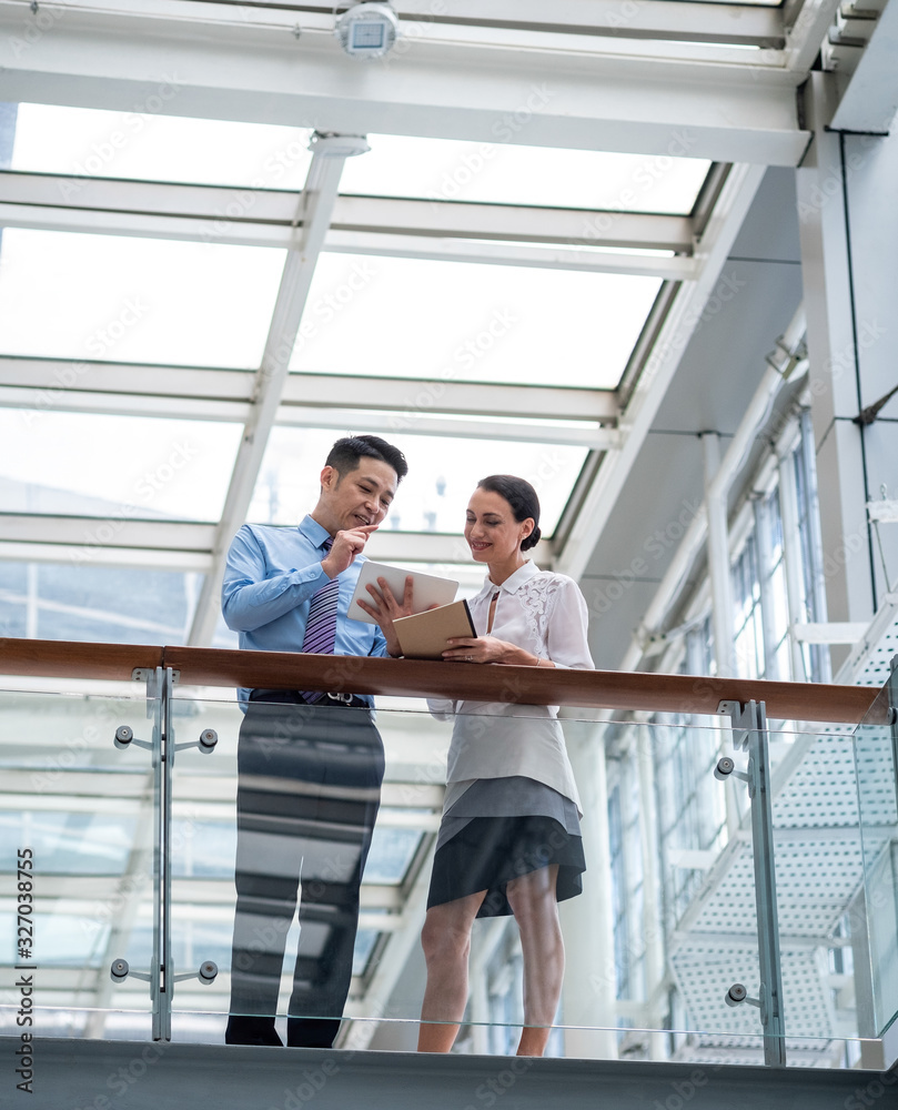 Talking strategy before the meeting stock photo.Shot of two colleagues talking together over a digital tablet while standing in a modern office Talking strategy before the meeting stock photo.Shot of two colleagues talking together over a digital tablet while standing in a modern office